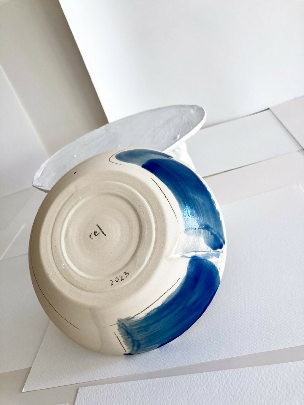 Bol en grès blanc avec touches bleu, vue intérieure, inscription sur le fond.