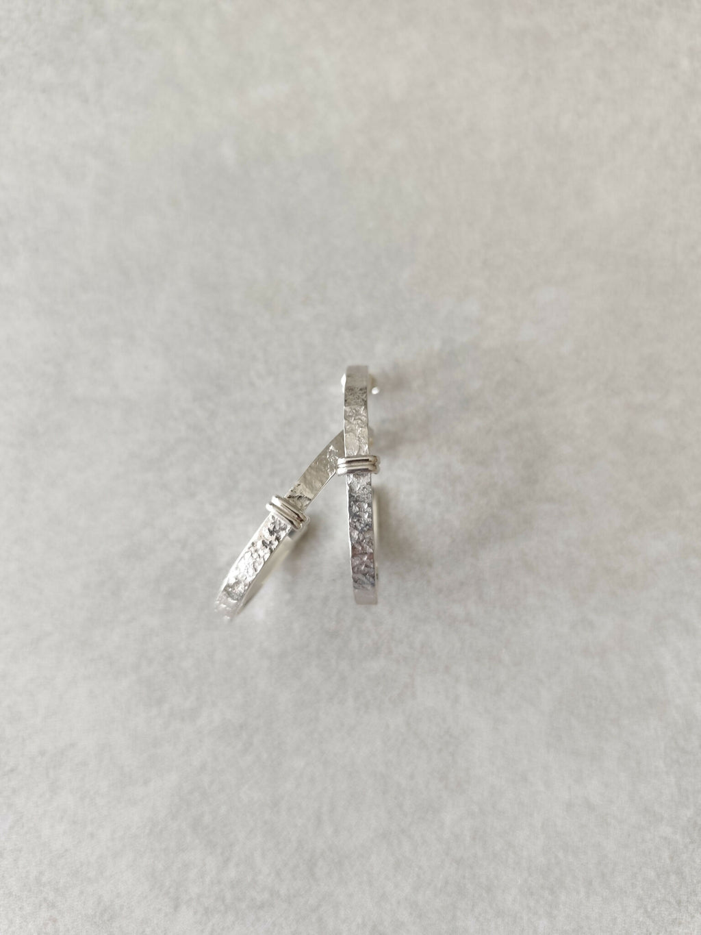 Boucles d’oreilles courbes argentées, fermoirs et côtés texturés bien visibles