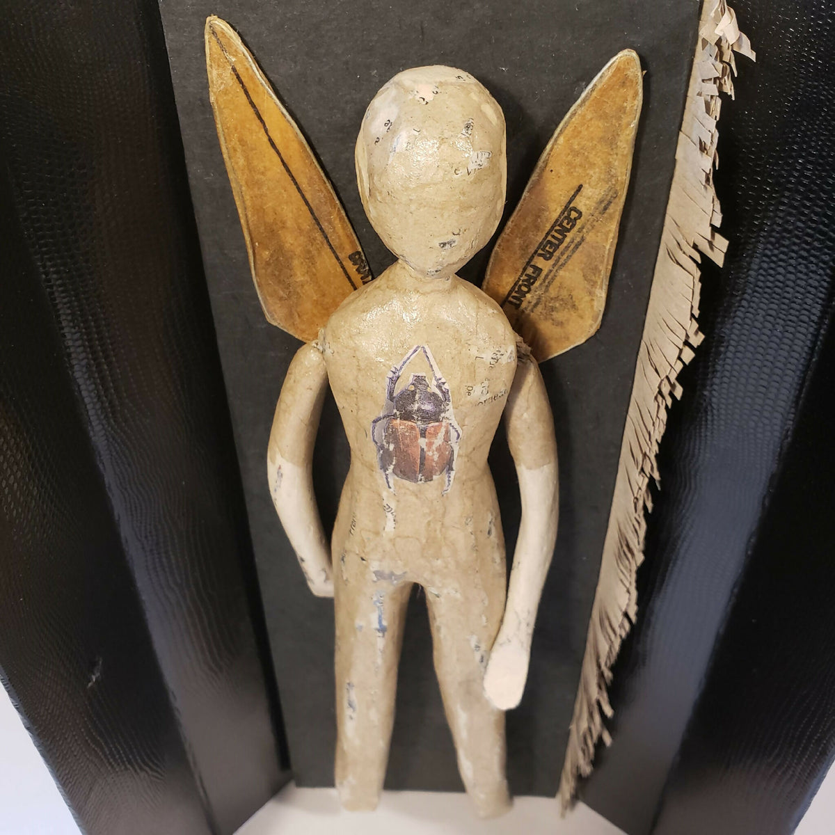 Poupée en papier beige à ailes dorées, figurine peinte visible