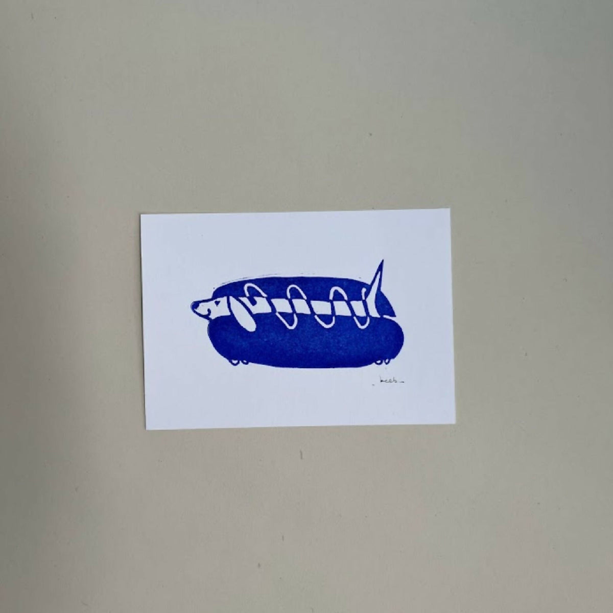 Linogravure A6 bleu ultramarine : chien sur hot-dog stylisé