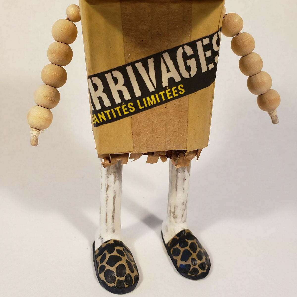 Sculpture bonhomme en carton : inscriptions « ARRIVAGES » et chaussures léopard