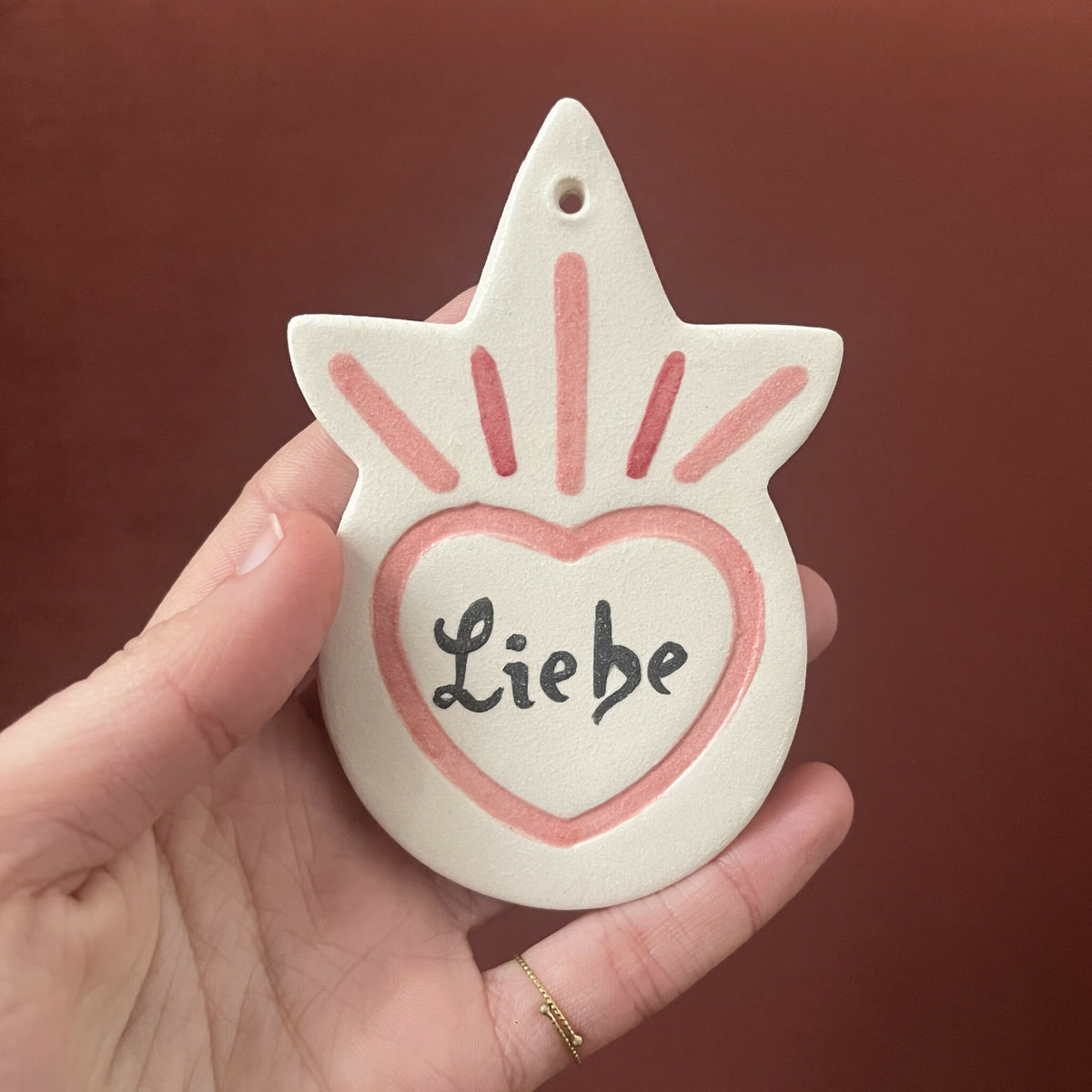 Ex-voto étoile peint, cœur « Liebe » rouge, rayons rose et bleu autour.