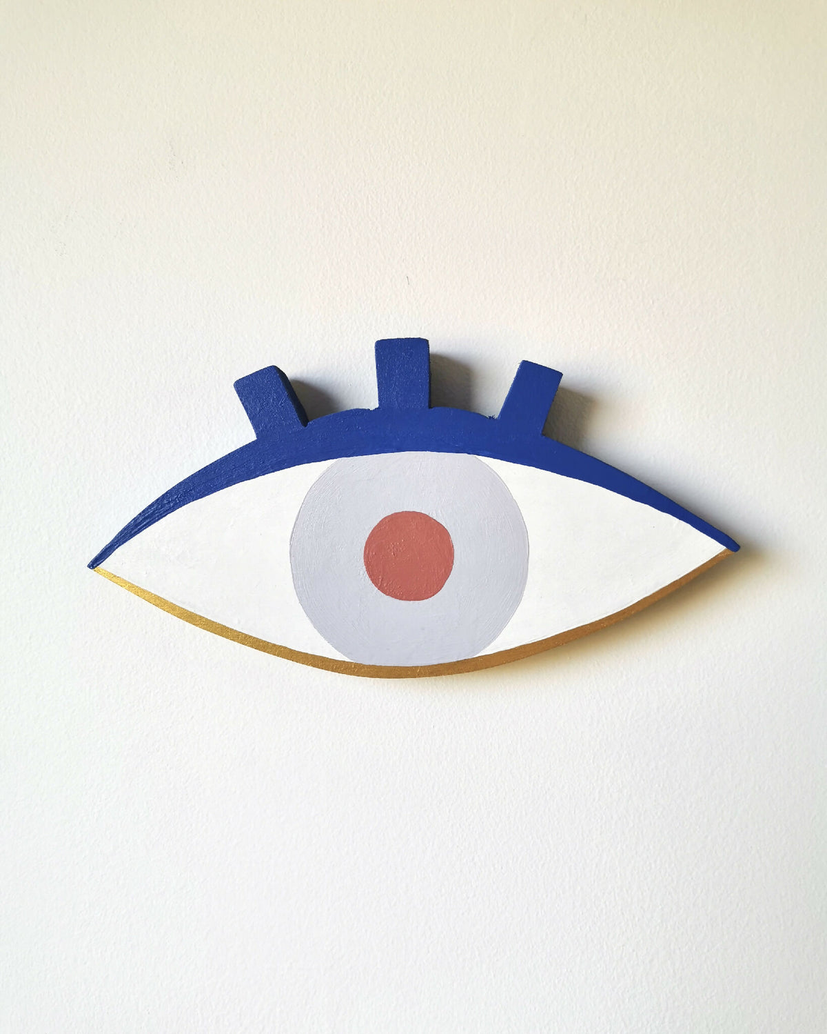 Décoration œil sur bois, contour bleu foncé, iris bleu clair, pupille orange.