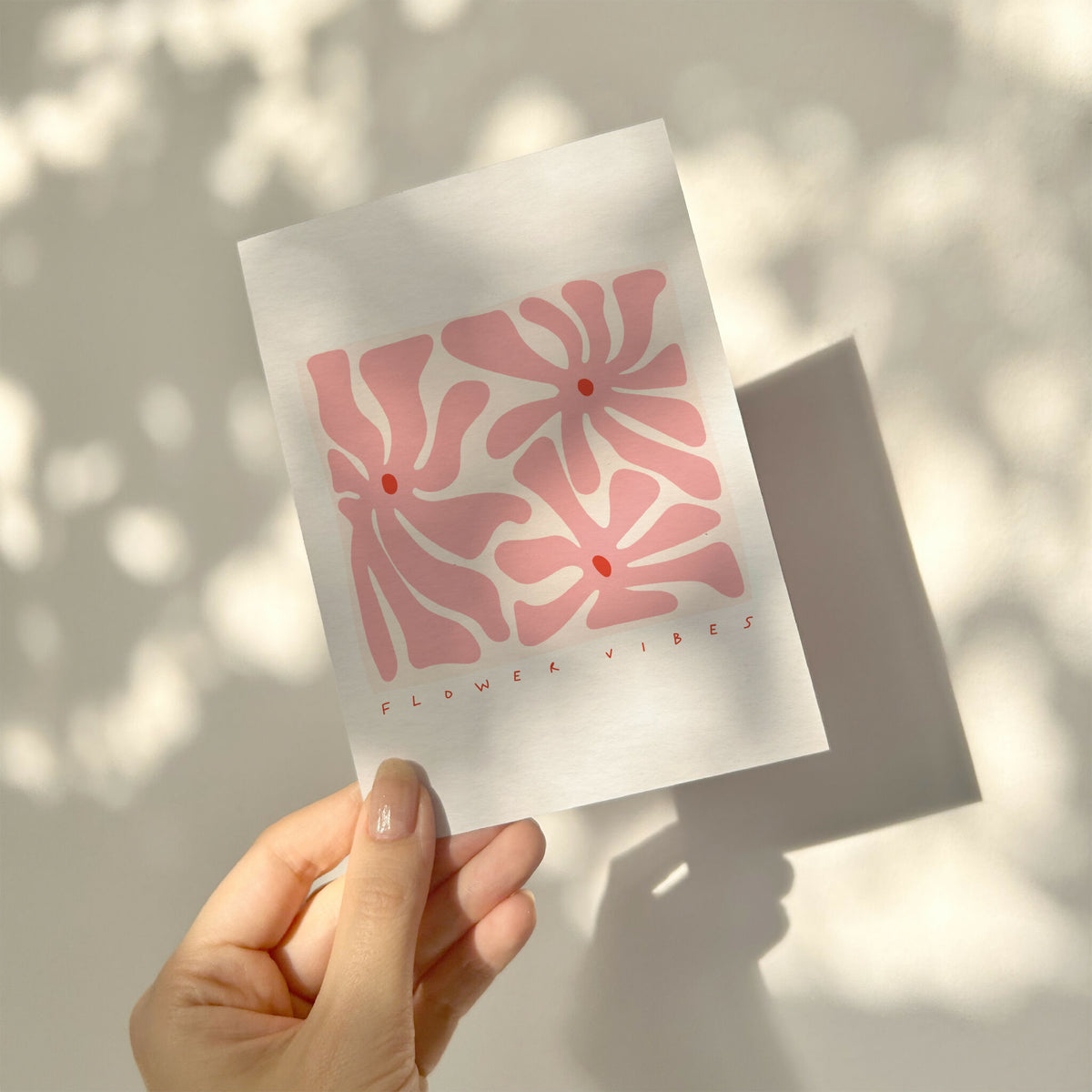 Carte illustrée fleurs abstraites rose, tenue dans une main.