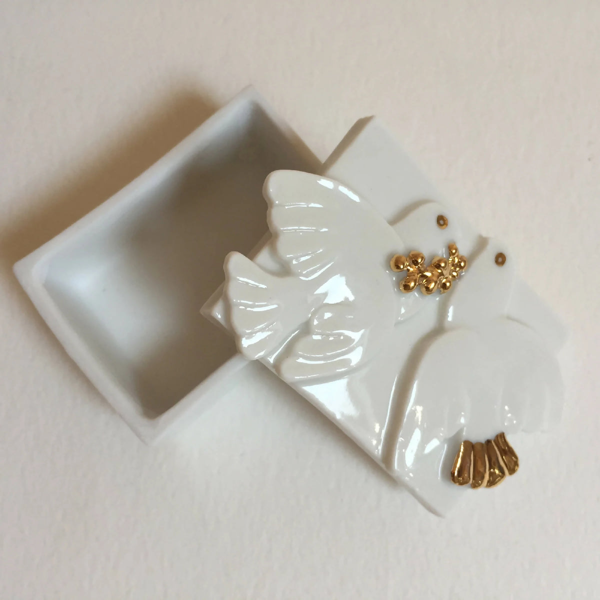 Boîte à bijoux blanche avec figurine de colombe laquée et détails dorés.