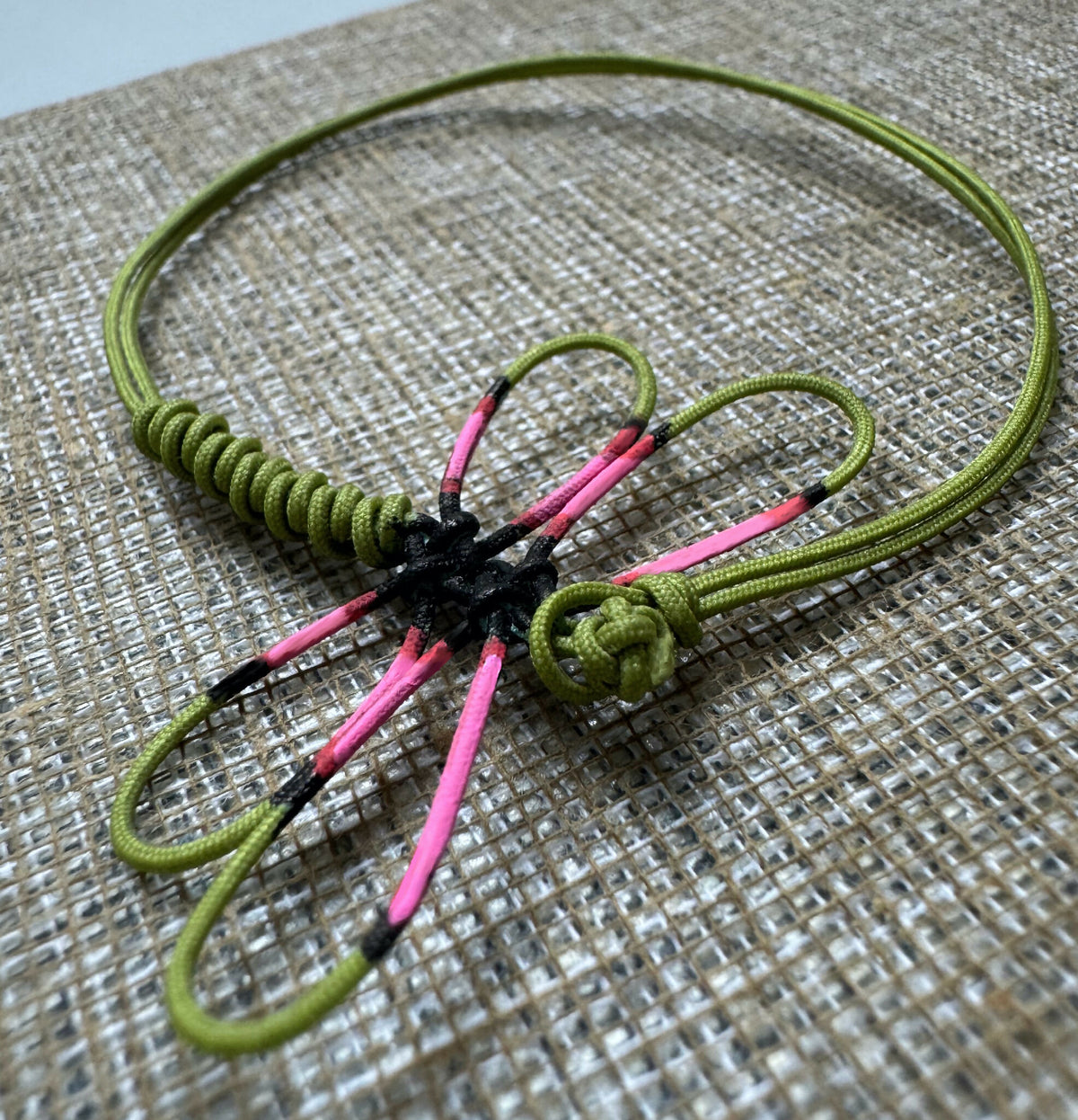 Bracelet en cordon vert tressé avec libellule peinte rose et noire, attache nouée.