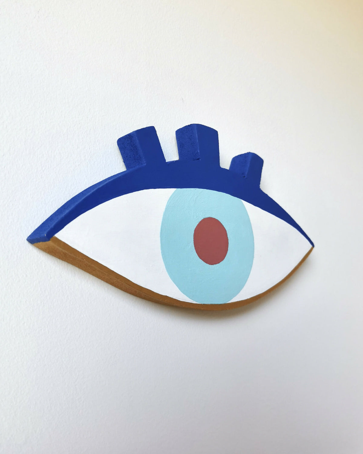 Décoration œil en bois, contour bleu, iris bleu clair et pupille rouge.