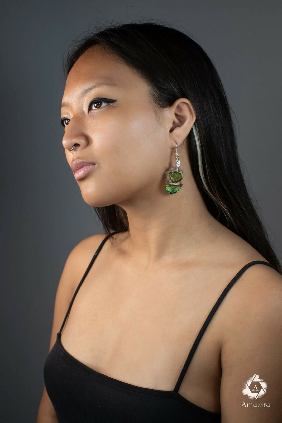Boucles d’oreilles plumes de paon vertes et bleues, monture acier argenté, portées.
