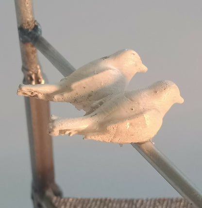 Deux oiseaux en métal blanc posés sur une barre du manège décoratif.