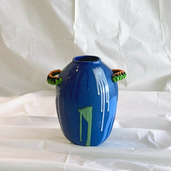 Vase amphore bleu brillant avec anses tressées verte et orange, motif vertical vert.