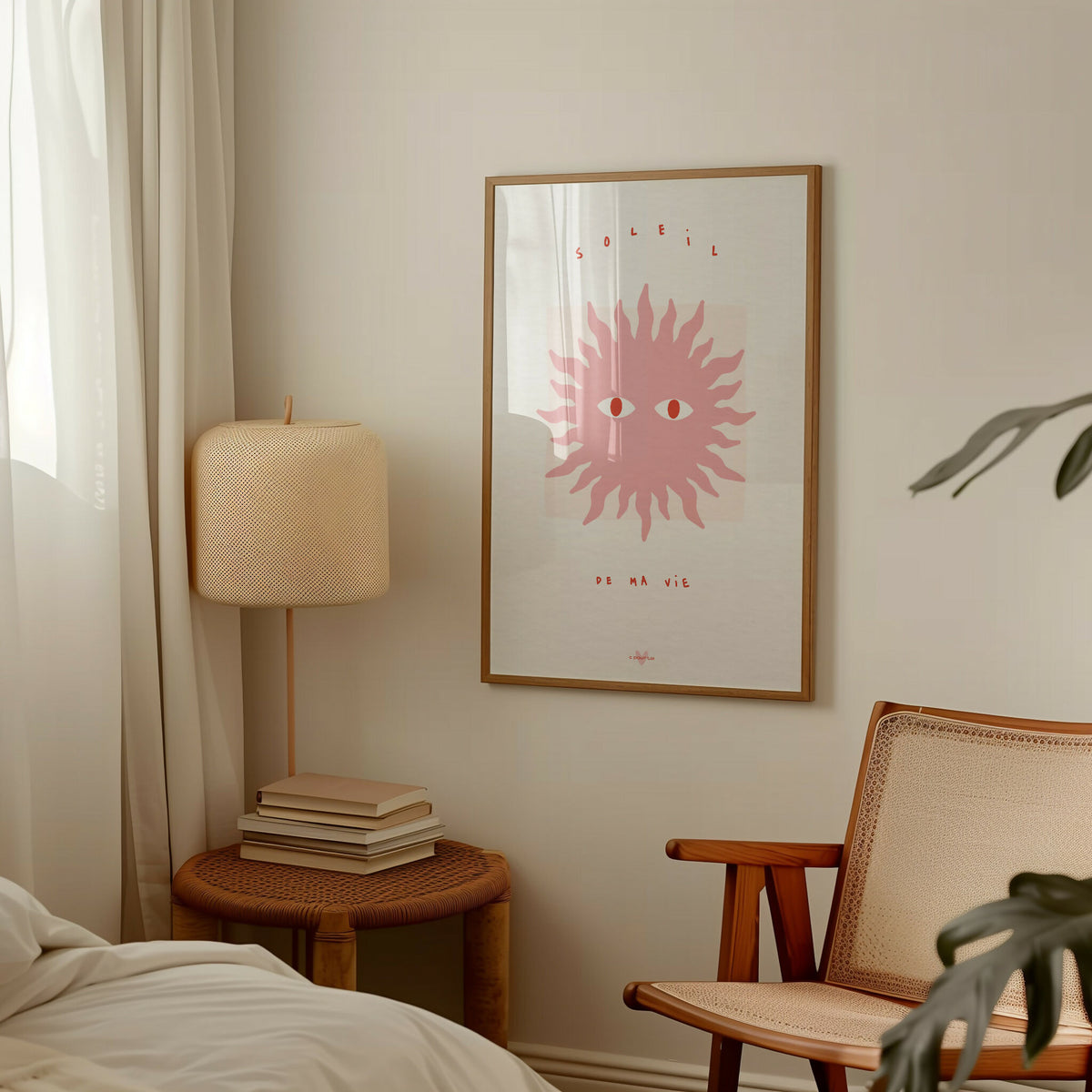 Affiche encadrée : soleil stylisé rose clair, yeux rouge-orangé, texte en bas.