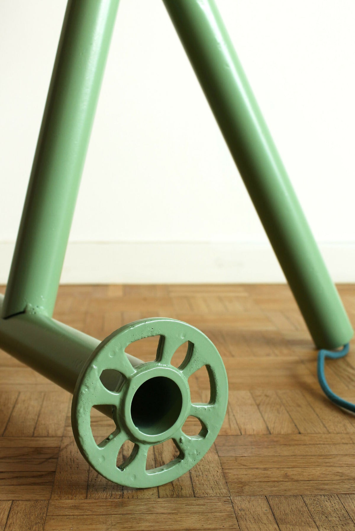 Lampe sur trépied vert, base avec roue métallique et pied tubulaire