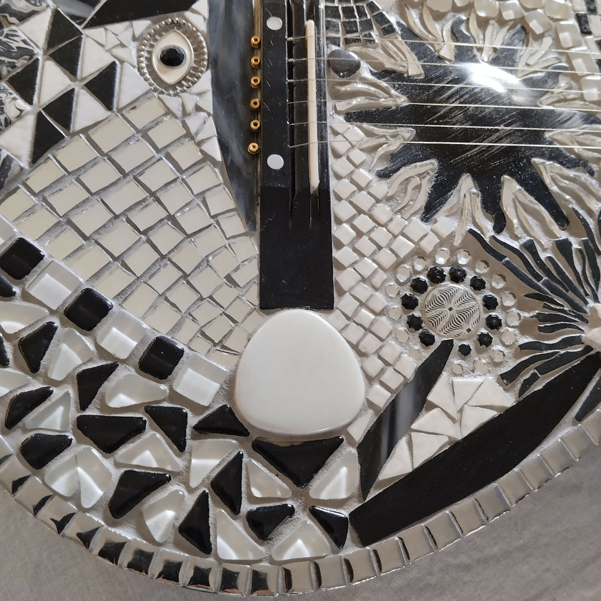 Corps de guitare à mosaïque noir et blanc, motif floral près du chevalet