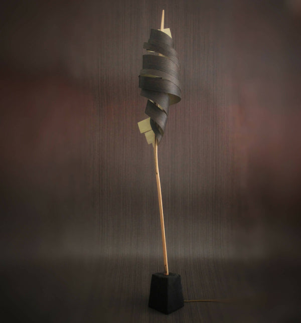 Lampe sur pied : spirale de rubans métalliques sombres sur tige bois, base carrée noire