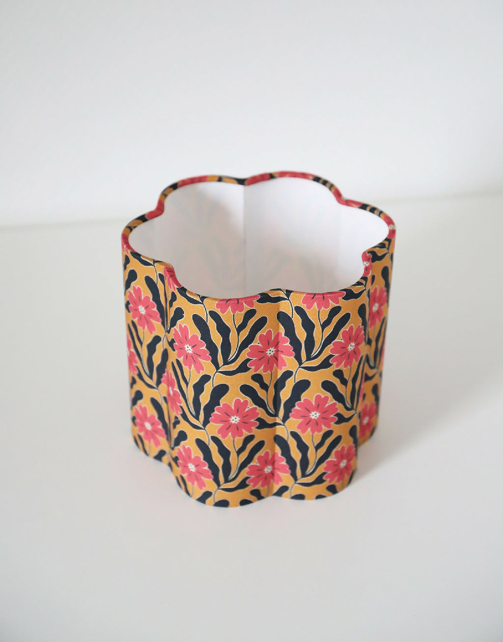 Abat-jour en tissu à fleurs roses, ouverture évasée, intérieur blanc, fond sombre