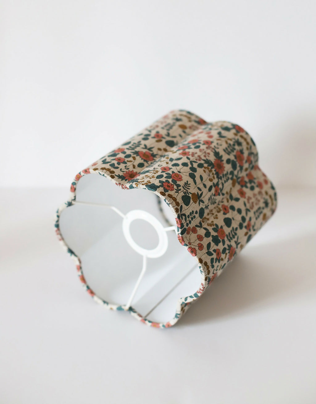 Abat-jour cylindrique en coton beige fleuri, vue oblique avec intérieur blanc.