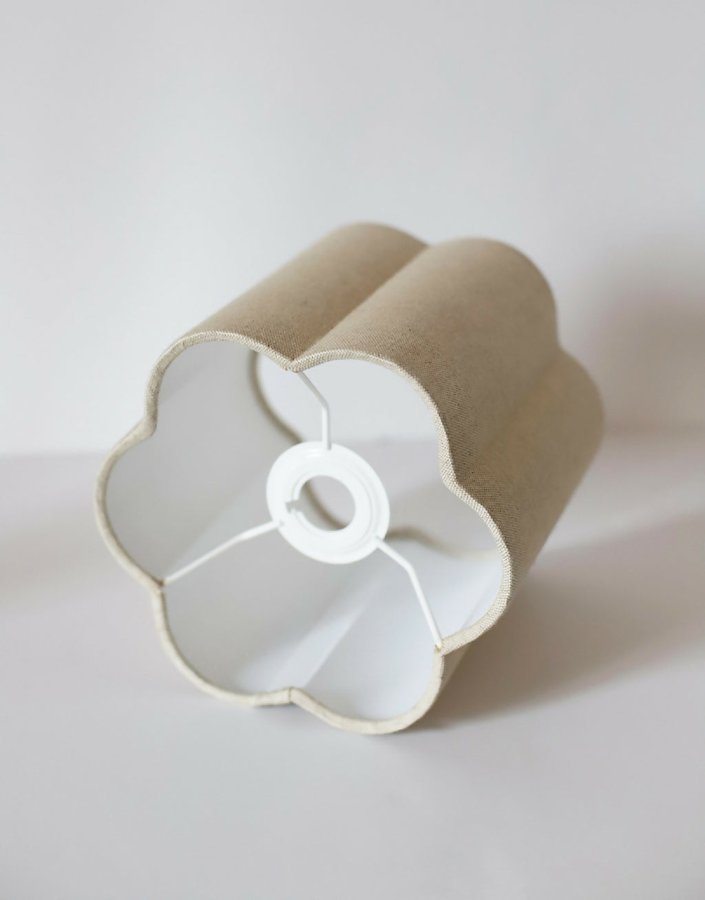 Abat-jour forme fleur en tissu beige, gros plan sur le support central blanc suspendu