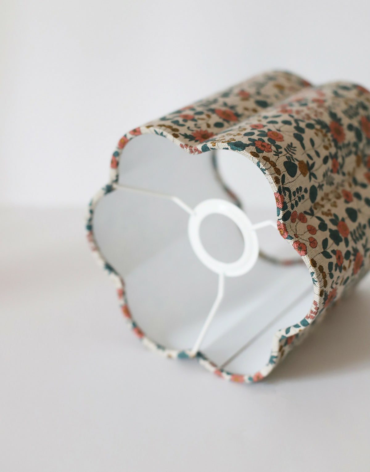 Abat-jour fleuri beige, vue rapprochée de l’intérieur blanc et de la structure.