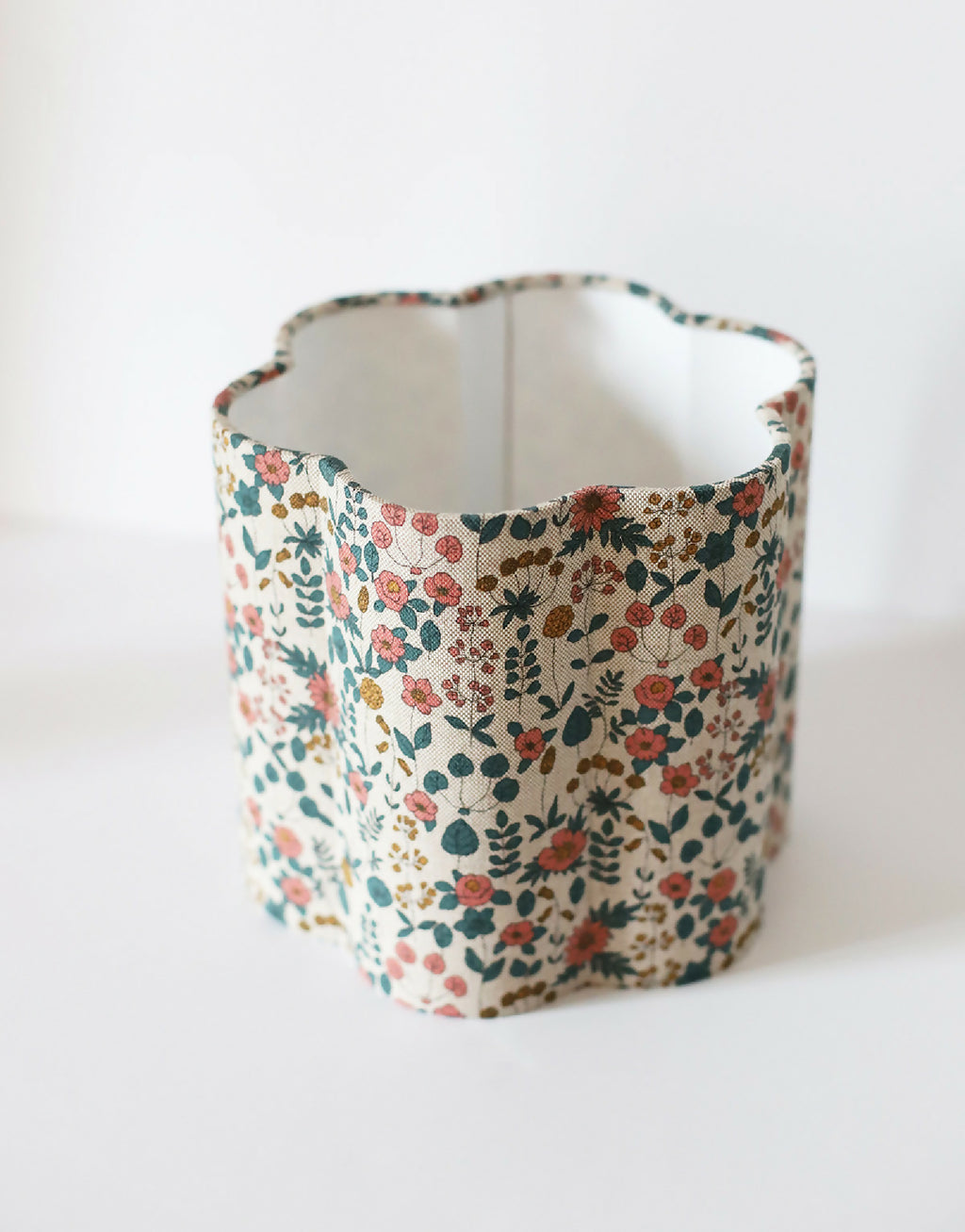 Abat-jour cylindrique en tissu beige fleuri, vue de profil.