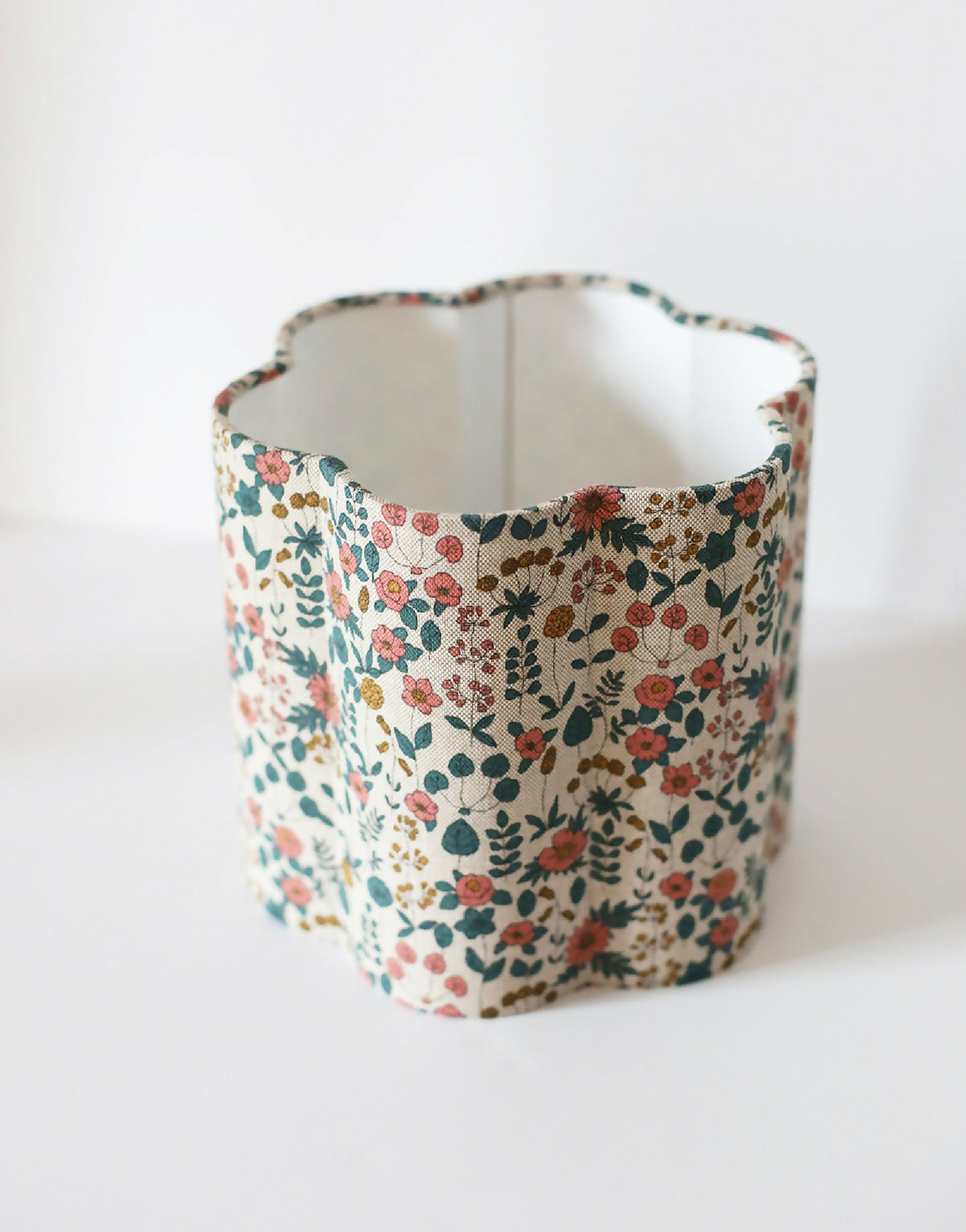 Abat-jour cylindrique en tissu beige fleuri, vue de profil.