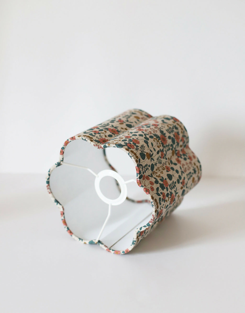 Abat-jour fleuri beige avec intérieur blanc et embase centrale blanche.