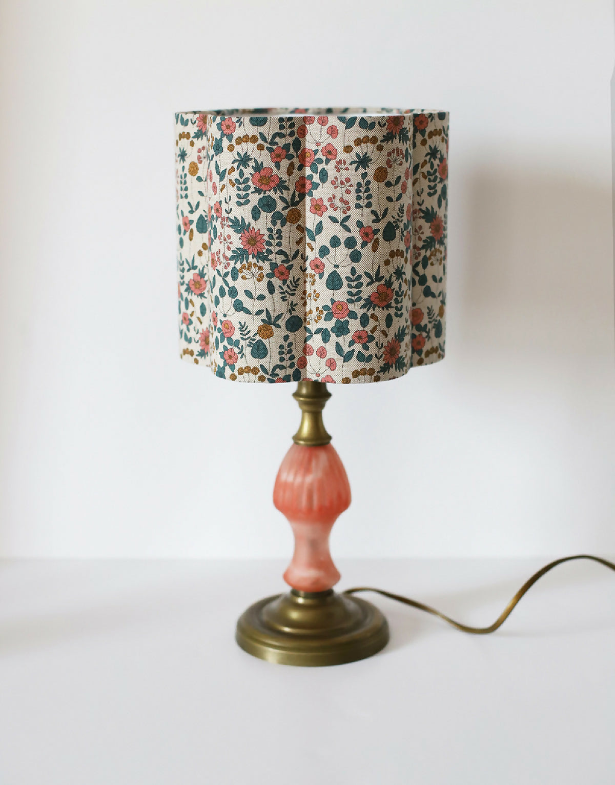 Abat-jour beige fleuri sur pied de lampe laiton avec base orange.