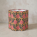 Abat-jour cylindrique beige à fleurs roses, motifs noirs ondulés.