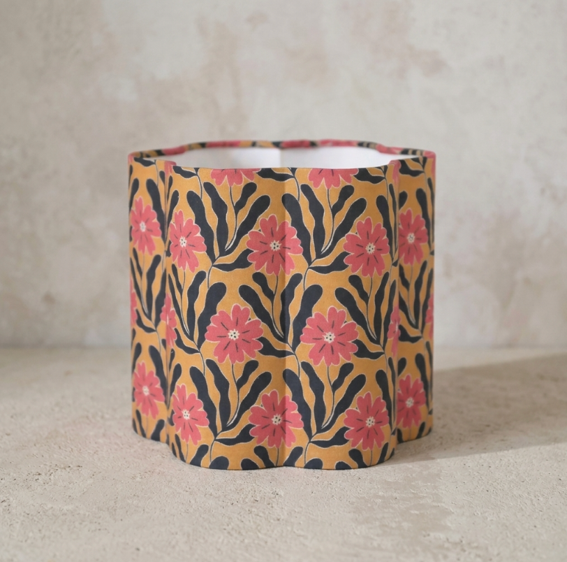 Abat-jour cylindrique beige à fleurs roses, motifs noirs ondulés.