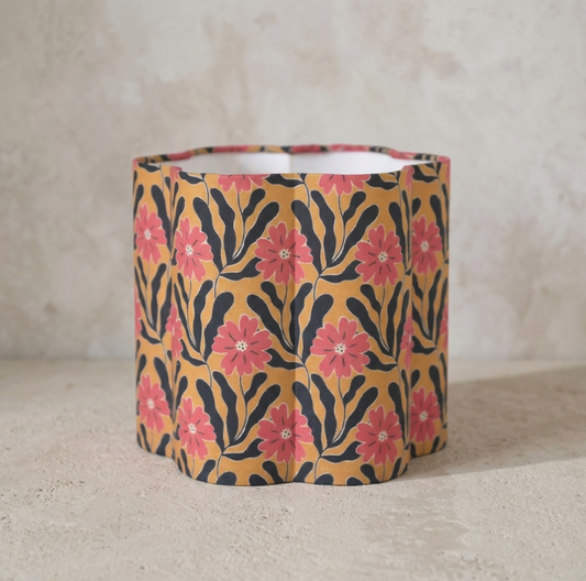 Abat-jour cylindrique beige à fleurs roses, motifs noirs ondulés.