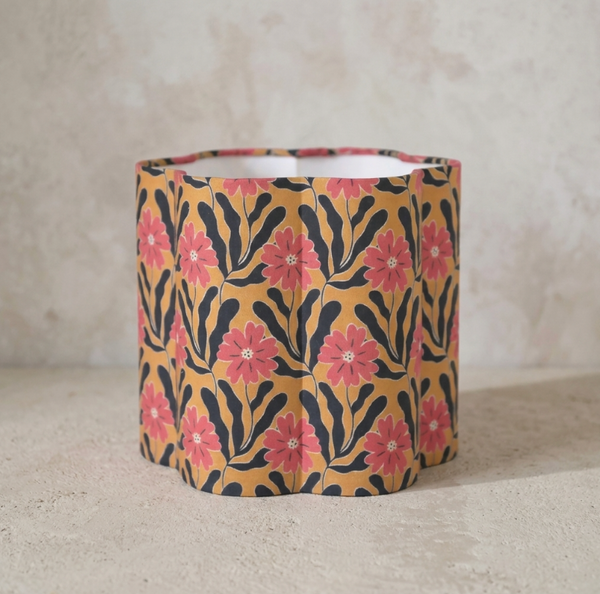 Abat-jour cylindrique beige à fleurs roses, motifs noirs ondulés.