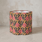 Abat-jour cylindrique beige à fleurs roses, motifs noirs ondulés.