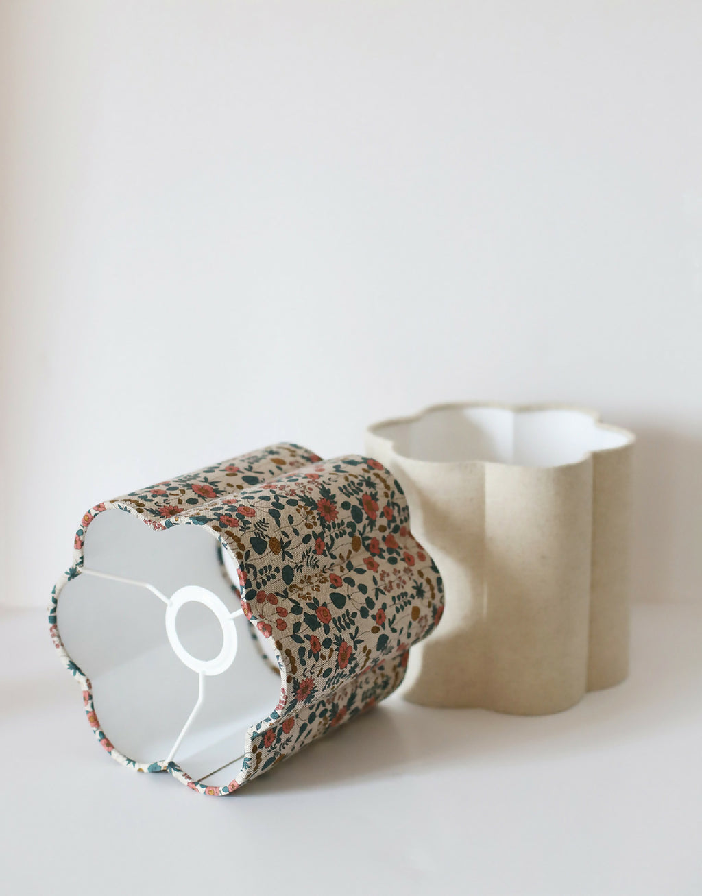 Abat-jour en tissu fleuri beige monté sur une base blanche.