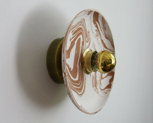 Applique murale ronde avec motif marbré beige et blanc et boutons dorés.