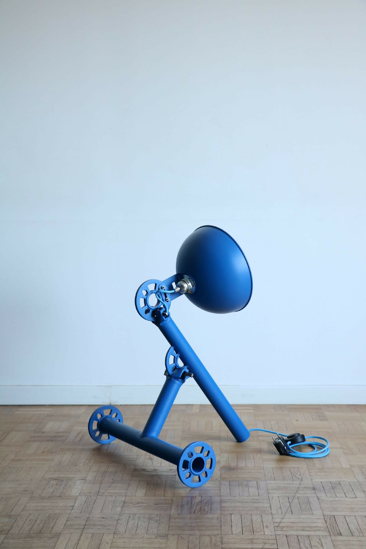 Lampe sur pied bleue avec abat-jour arrondi et structure à roues