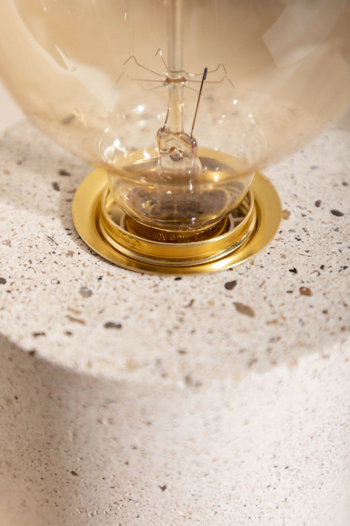 Lampe à poser : gros plan sur la base dorée et l’ampoule globe claire