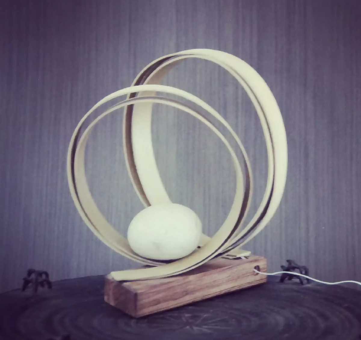 Spirale décorative : anneaux lumineux en métal sur socle en bois, avec boule blanche