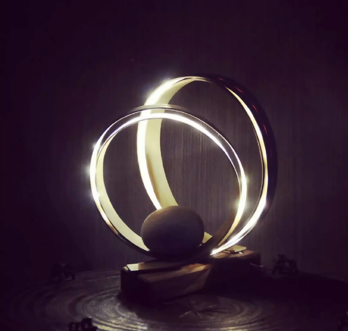 Spirale décorative : anneaux lumineux métalliques sur socle en bois, avec boule sombre