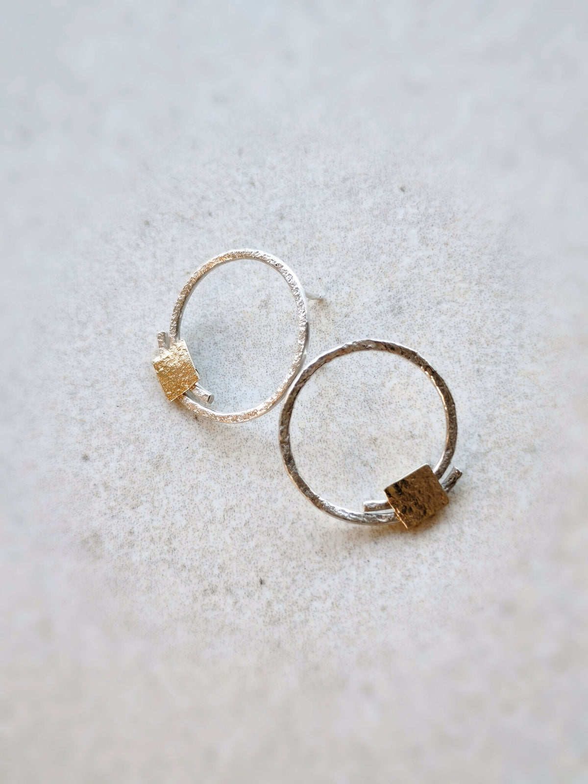 Paire de boucles d’oreilles créoles argentées et pastilles carrées dorées, vue de côté