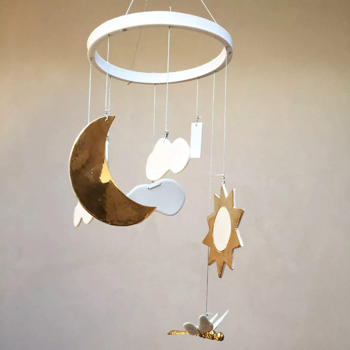 Mobile de naissance avec lune dorée, nuages bleus et étoiles, anneau blanc.