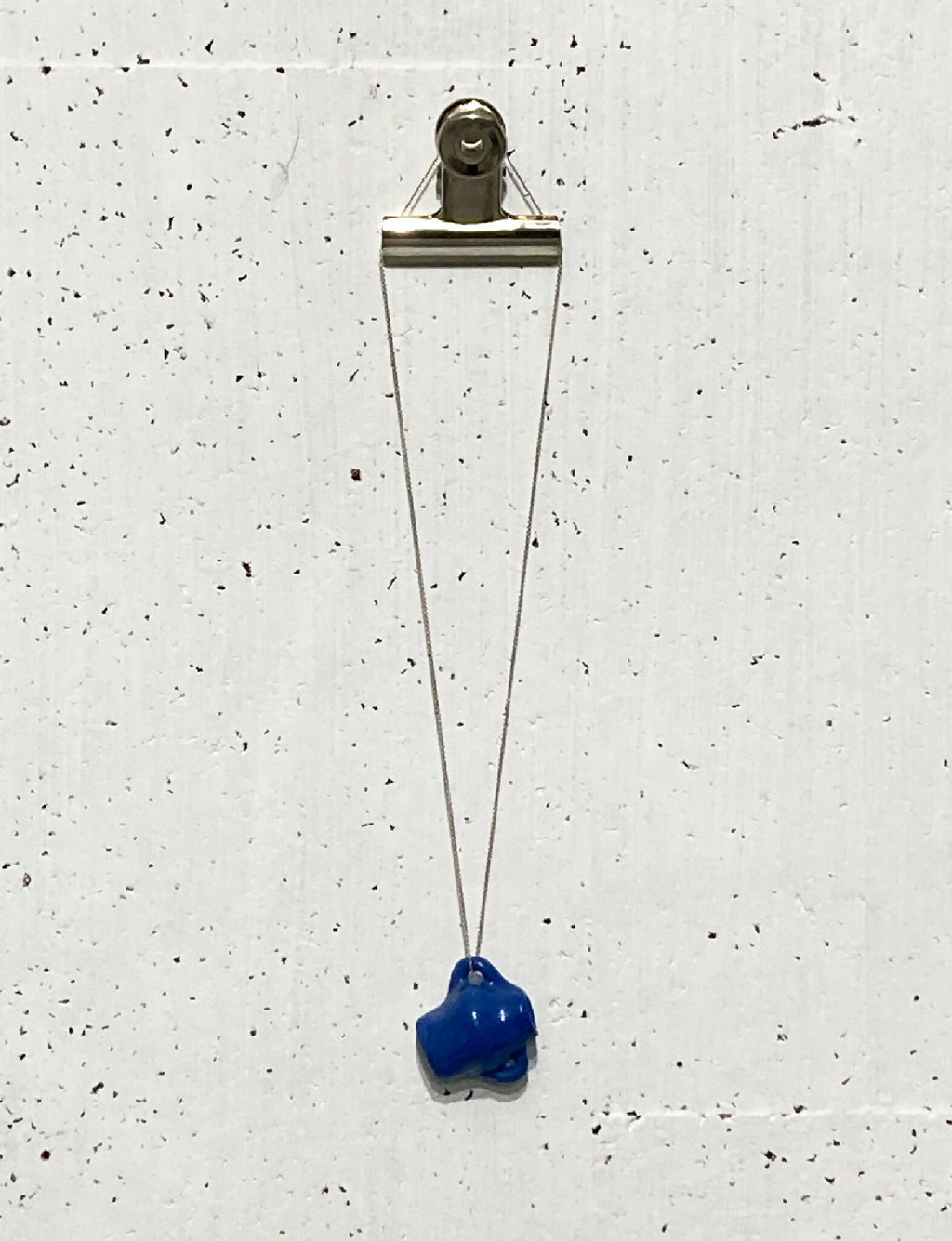 Pendentif en porcelaine bleue sur chaîne en argent avec fermoir métallique.