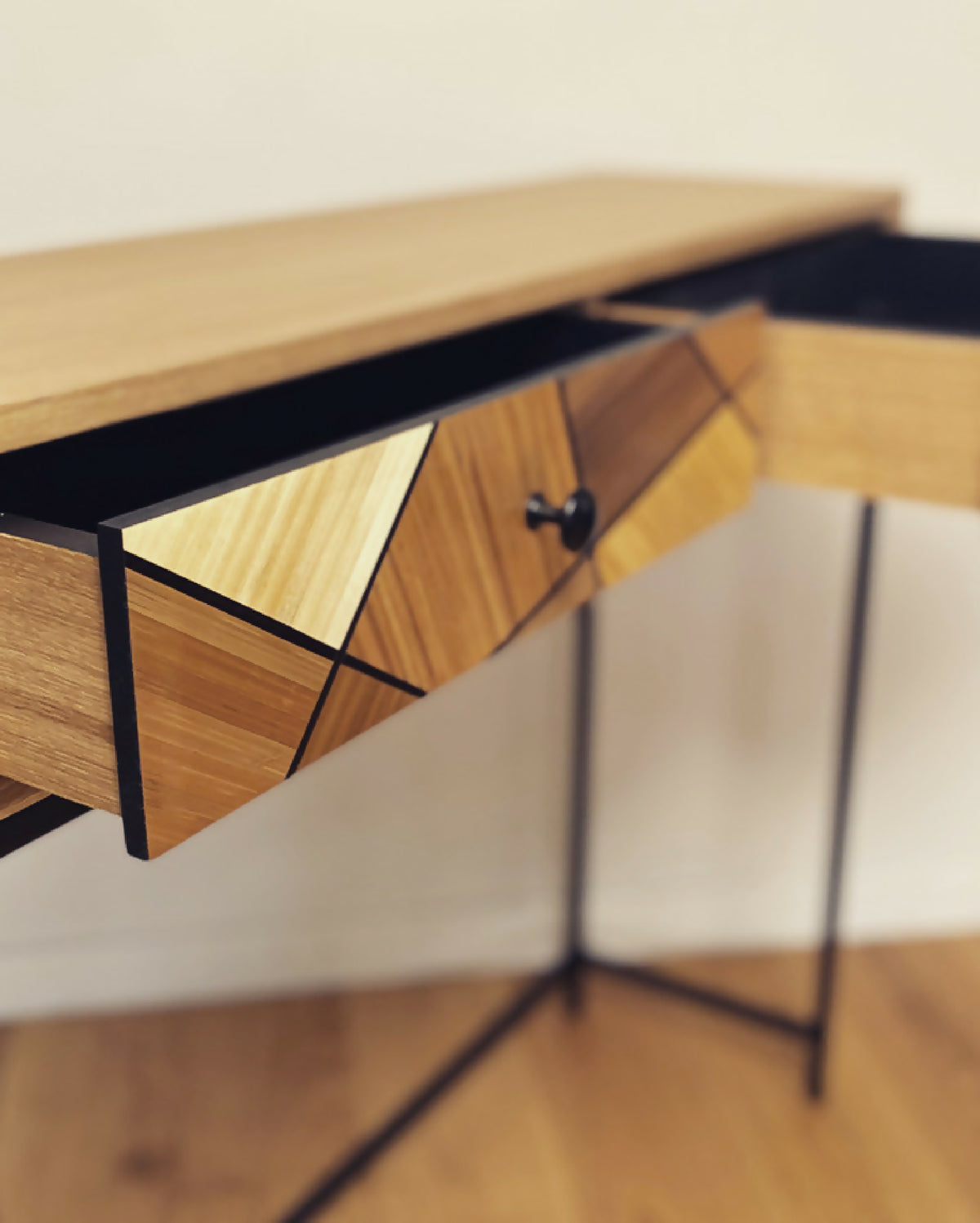 Détail de console en chêne : tiroir à losanges et bouton noir, structure noire