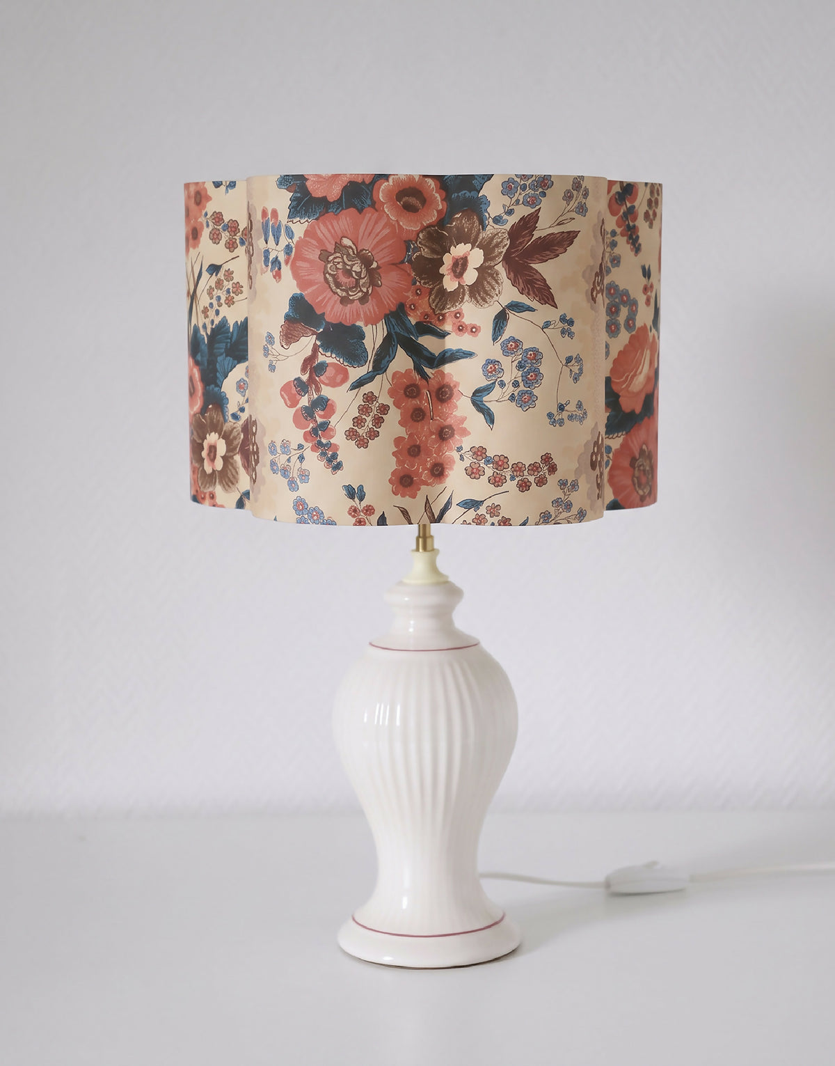 Abat-jour fleuri crème et multicolore, posé sur une lampe blanche avec interrupteur.