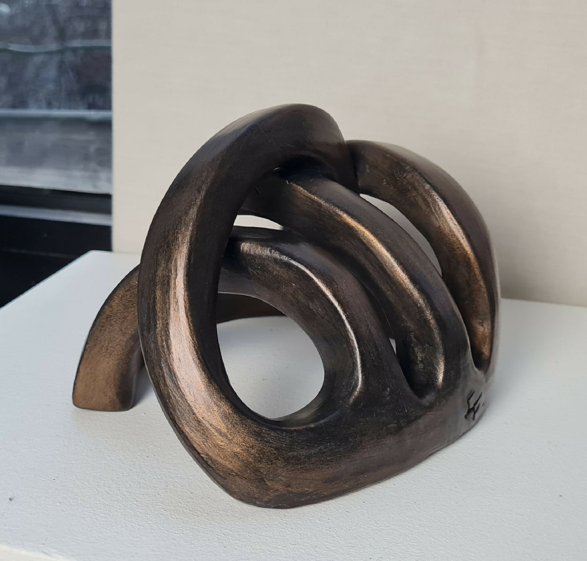 Sculpture abstraite en métal foncé, formes courbes superposées, vue de trois-quarts