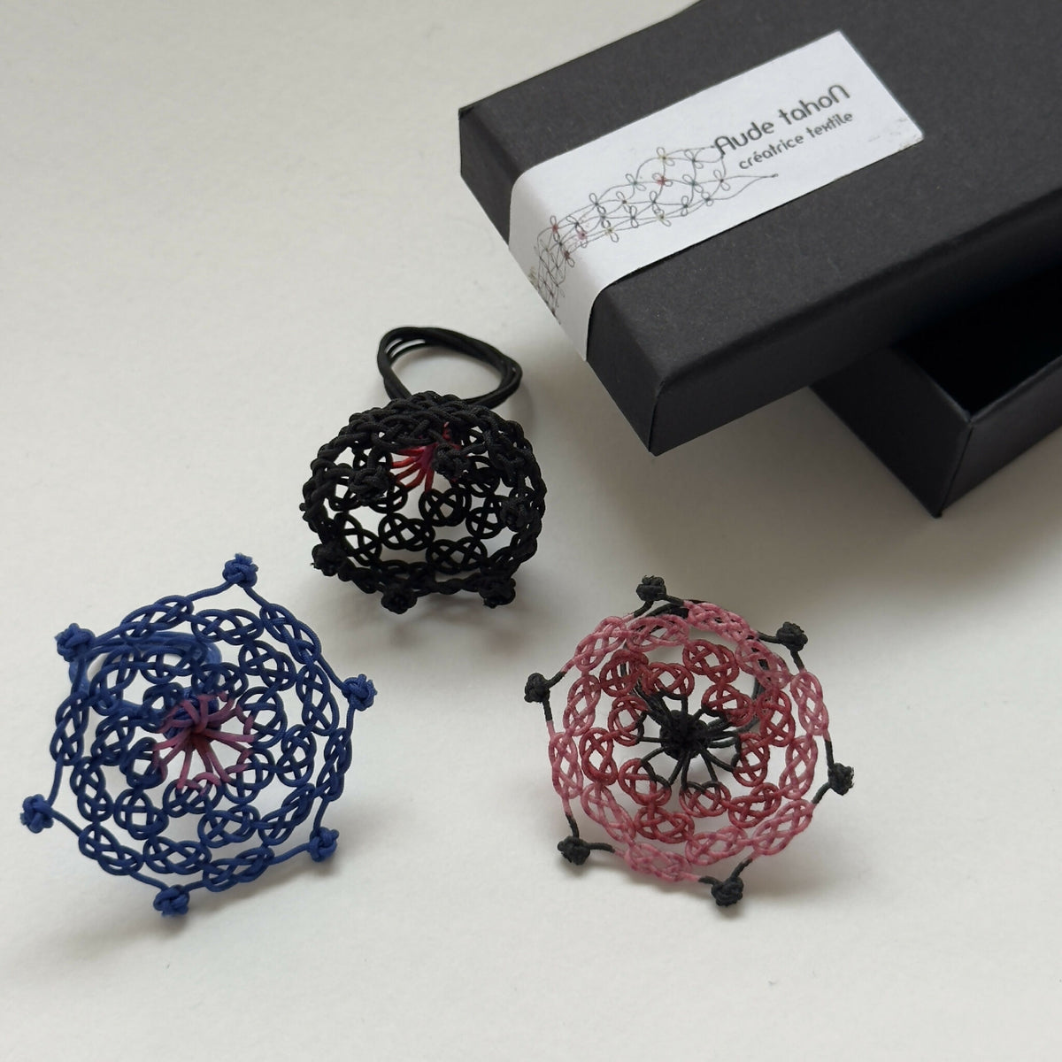 Bague noire en résille tressée, étoile rouge au centre, parmi autres coloris