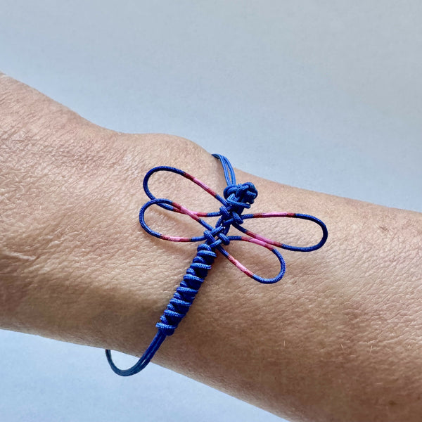Bracelet fin bleu avec motif de libellule rose, nœuds décoratifs et cordon réglable.
