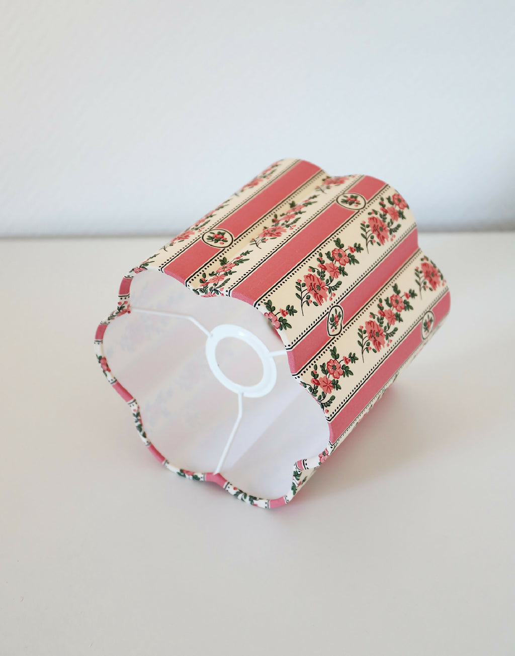 Abat-jour forme fleur rayé rose, motifs floraux, vue de profil avec intérieur blanc.
