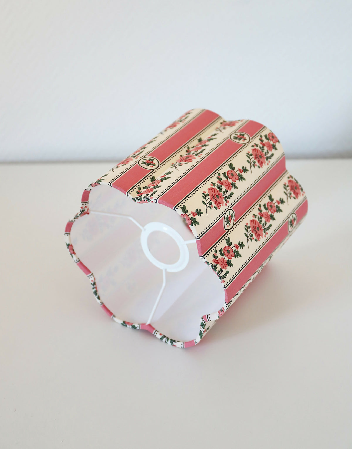 Abat-jour forme fleur rayé rose, motifs floraux, vue de profil avec intérieur blanc.