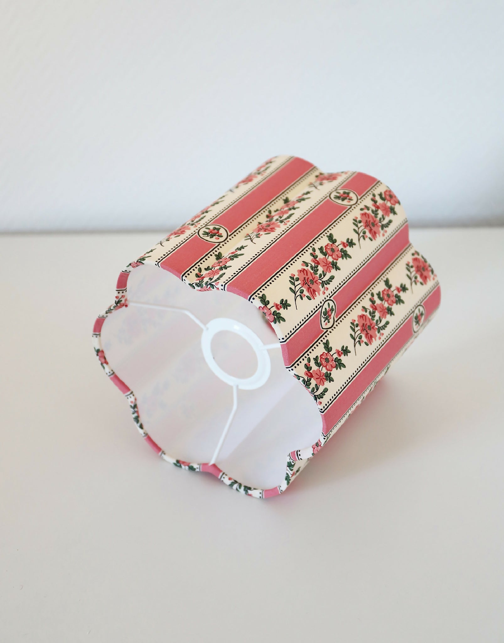 Abat-jour forme fleur rayé rose, motifs floraux, vue de profil avec intérieur blanc.