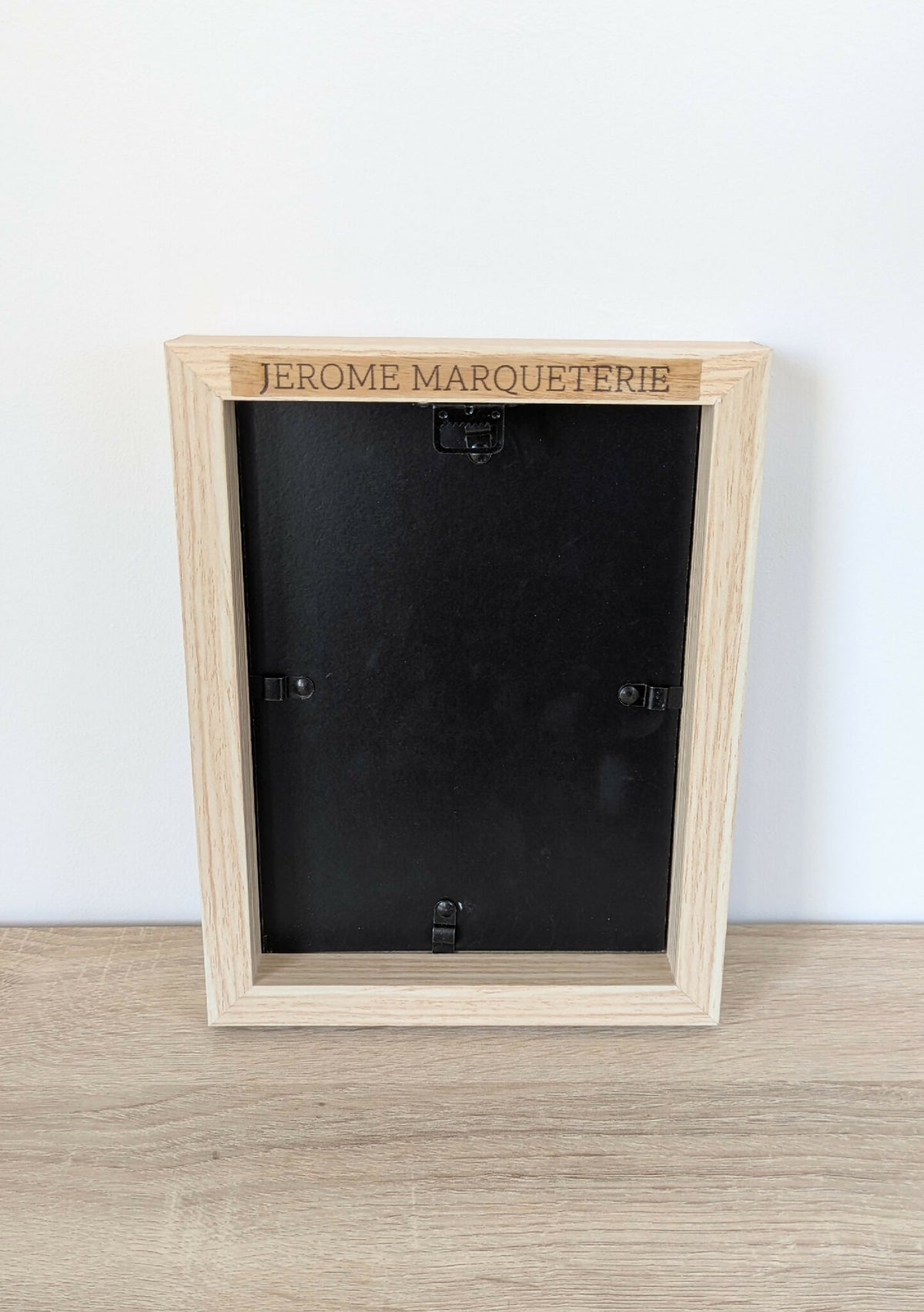 Dos de tableau en bois clair, plaque « JEROME MARQUETERIE » et fixations