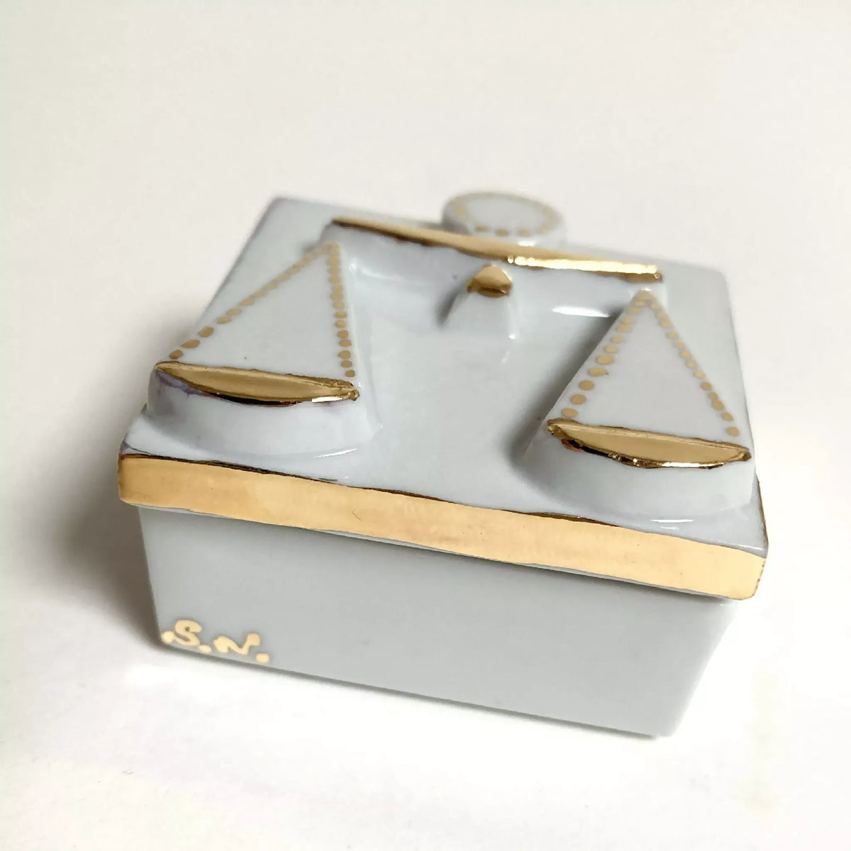 Boîte à bijoux en porcelaine blanche, motif balances dorées et inscription dorée « S.N. ».